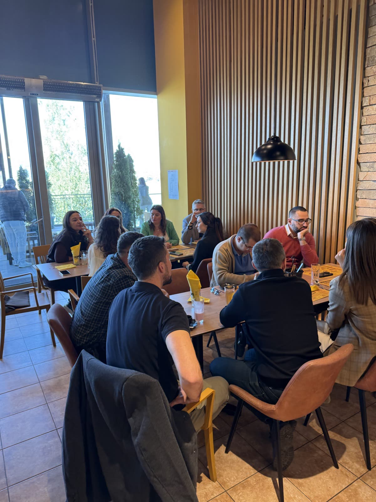 Groups gathered around tables beside the restaurant windows