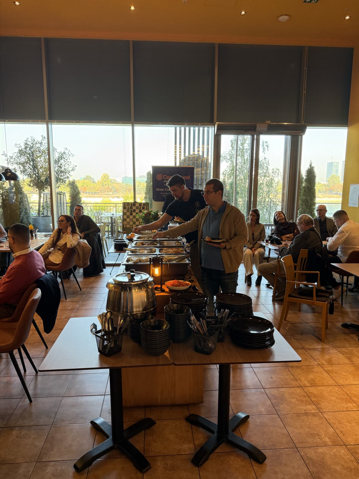 Breakfast buffet with people serving food and talking at tables