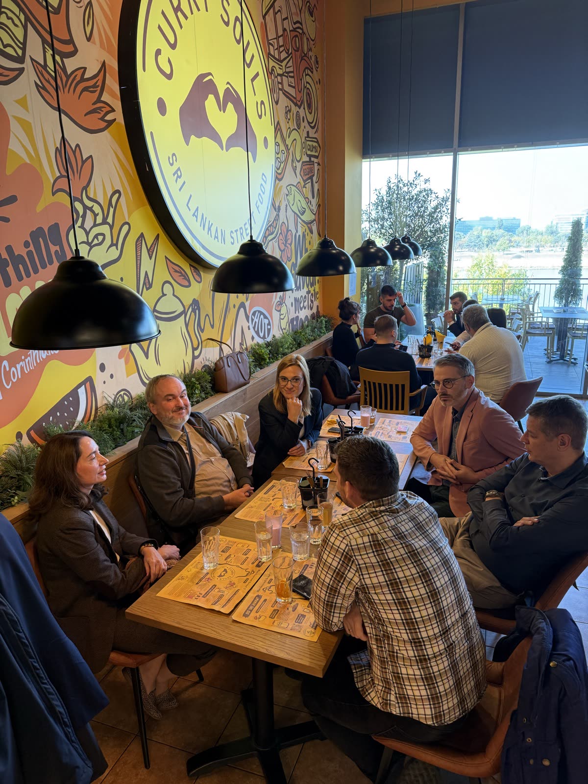 People talking around a restaurant table beneath pendant lights